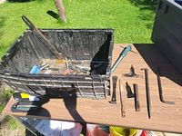 Overall lot showing crate filled with assorted hand tools and several laid out on table