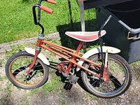 Left side of orange Winfield child's bicycle showing fenders, seat, handlebars and wheels
