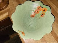 Top view of scalloped green bowl with orange floral motif
