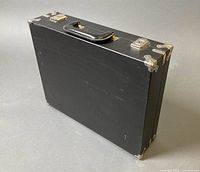 Closed black briefcase showing exterior finish, handle and hardware