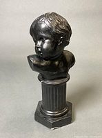 Front view of black infant bust on fluted column pedestal