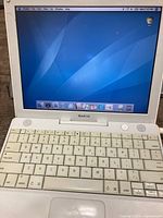 Laptop open and powered on displaying Mac OS X desktop and keyboard visible