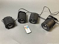 Four black cylindrical LED water-effect lights with remote control shown powered off