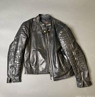 Front view of black leather motorcycle jacket showing collar, zipper, pockets and padded sleeves