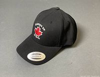 Full view of black snapback cap showing front embroidery and brim sticker