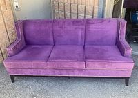Front view of purple velvet sofa with three cushions and nailhead trim