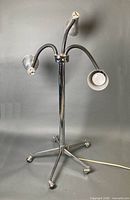 Full view of chrome floor lamp with three gooseneck arms on wheeled base