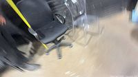 Black mesh task chair alongside clear acrylic chair, showing both items in lot