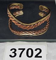 Top view of copper and brass braided cuff bracelet showing open cuff ends and mixed-metal twist