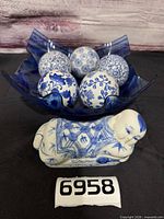 overall view of bowl containing five porcelain orbs with figurine in front