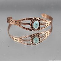 Front view of copper cuff with turquoise cabochon and stamped designs