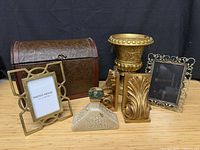 Group shot of chest, urn, bookends, frames and bottle