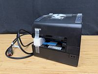 Front and left side view of printer with cables, tape and foam visible