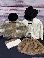 Group shot of both faux fur jackets, two hats, faux fur handbag, suede pouch and brooch