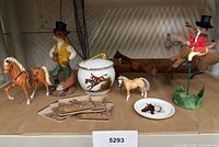 Full lot on shelf showing jar, fox figurine, two toy horses, whirligig, plate, coasters