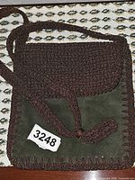 Front view showing olive suede body, brown braided flap and strap