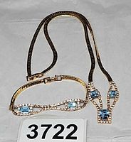 Necklace and bracelet laid flat showing gold-tone metal, blue stones, rhinestones, and clasps with lot number visible