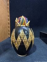 Front view showing black egg body with gold lattice and marble crown