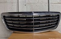 Front view of grille showing chrome frame, slats, emblem mount