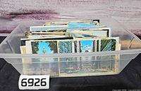 Plastic bin containing stack of assorted postcards