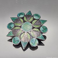 Front view showing floral sunburst design and green/teal enamel