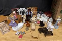 Overview of assorted dollhouse furniture, figurines and accessories on surface