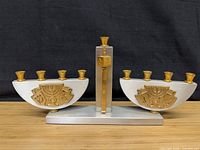 Front view of silver and gold menorah showing candle cups and decorative panels