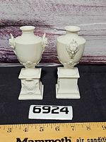 Pair of ivory porcelain urns front view with ruler and lot number for scale