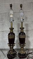 Full view of both matching neoclassical table lamps with bulbs and finials attached