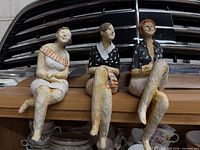 All three paper mache figurines seated on shelf edge