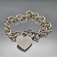 Bracelet laid in a circle showing double chain, toggle clasp, heart charm
