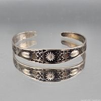 Sterling silver cuff bracelet front view showing stamped motifs and patina