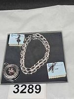 Bracelet, Happy Birthday charm and two dancer charms displayed on black surface with tags visible