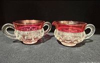 Open sugar bowl and creamer showing handles, clear bodies, ruby flash rims
