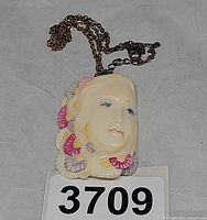Front view of ivory resin face pendant on gold-tone chain