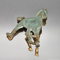 Front view of bronze and brass galloping horse brooch showing verdigris patina
