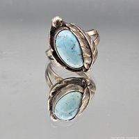 Front angled view showing turquoise cabochon, floral leaf motif and metal colour