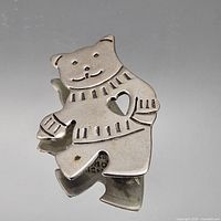 Front view of sterling silver cat brooch showing heart cutout and engraved sweater details