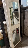 Full view of cabinet showing two mirrored doors and white painted frame