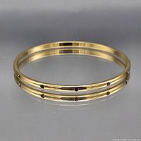 Gold-tone bangle showing green and red stones around band