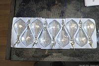 Tray holding eight of the clear faceted drop crystals showing overall shape and connectors