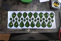 Tray holding sixteen emerald green faceted crystal drops with connectors