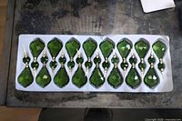 Tray with 16 emerald green chandelier crystals in packaging