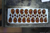 Tray holding 17 honey amber faceted drops with connector gems and stems