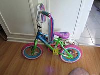 Left side view of green and blue Disney Encanto bicycle with multicolor streamers
