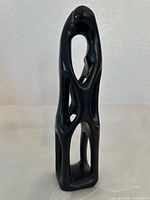 Front view of tall black soapstone abstract figure sculpture showing overall form and openings