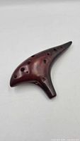 Top view of dark brown ceramic ocarina showing finger holes and body shape