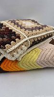 Folded stack of both crochet afghans showing colour patterns and edging