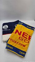 Two folded golf towels showing front graphics