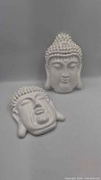 front view of both white ceramic Buddha head wall hangings